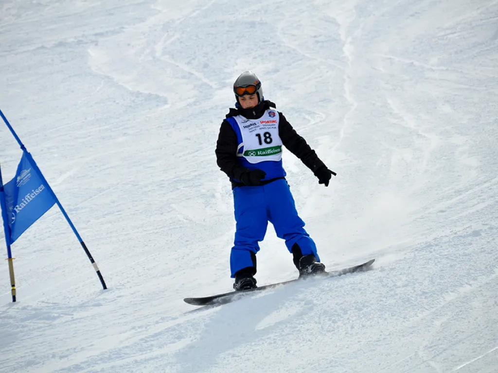 Snowboarder mit Startnummer 18 fährt am blauen Tor vorbei.